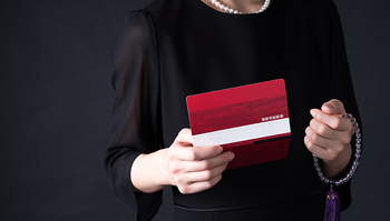 銀行通帳の残高を確認する葬儀参列者